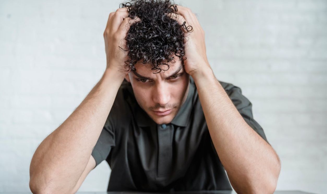 Young Upset Man Sitting Holding His Head in Hands