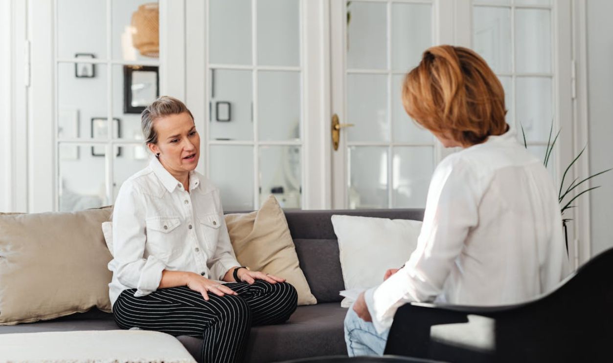 Woman in White Long Sleeves and Black Stripes Pants Talking to Woman in White Long Sleeves Top