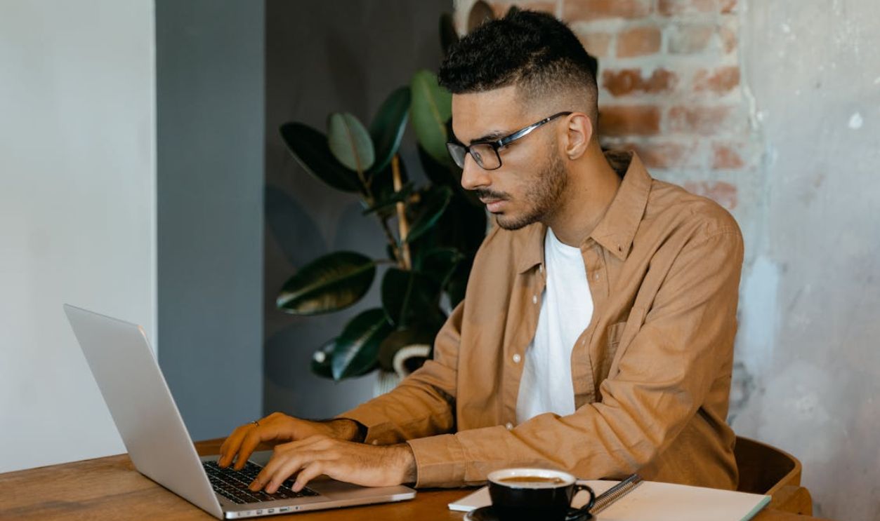 Man in Brown Dress Shirt Typing on a MacBook Pro