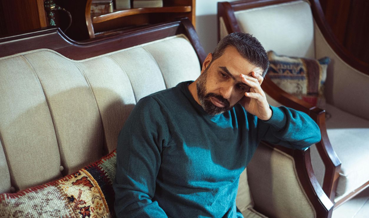Thoughtful man sitting on a vintage sofa indoors