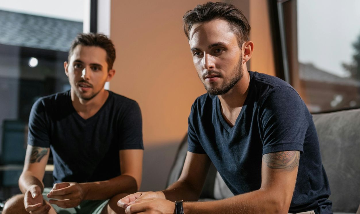 Two Men Sitting on Gray Couch and Watching