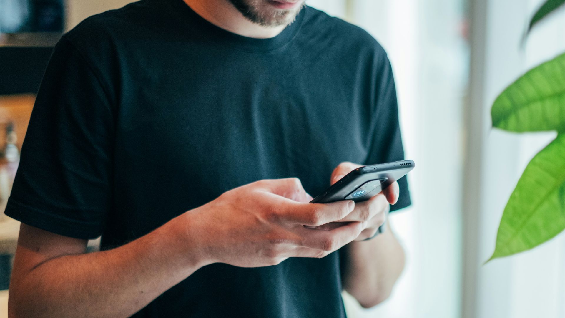 man in black crew-neck top using smartphone