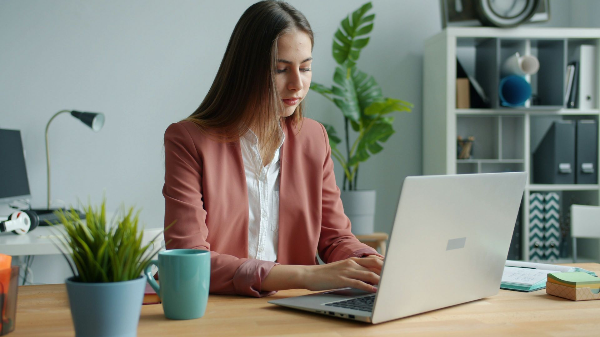 Woman working on laptop at office desk.