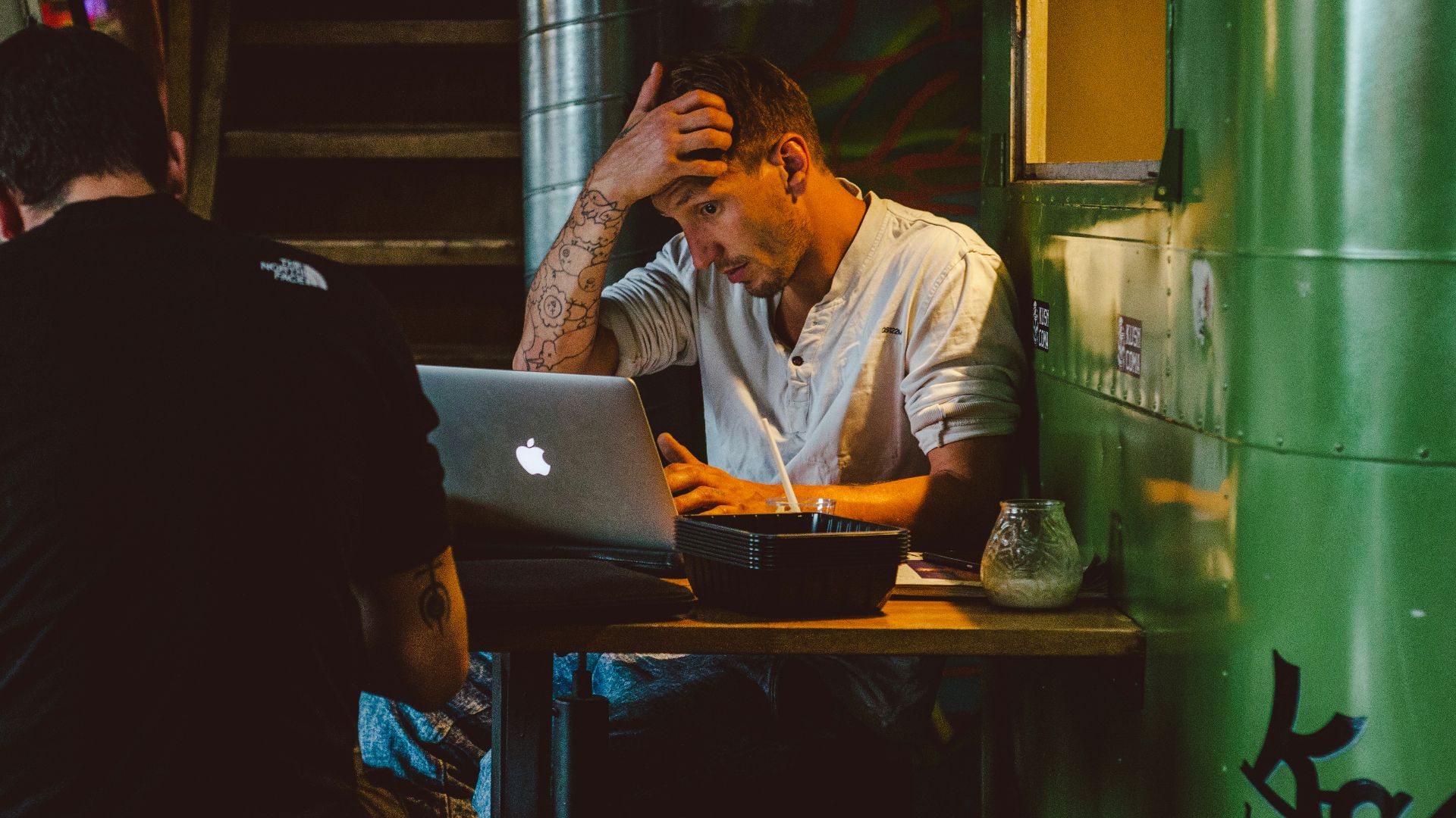 man in front of silver MacBook while scratching his head