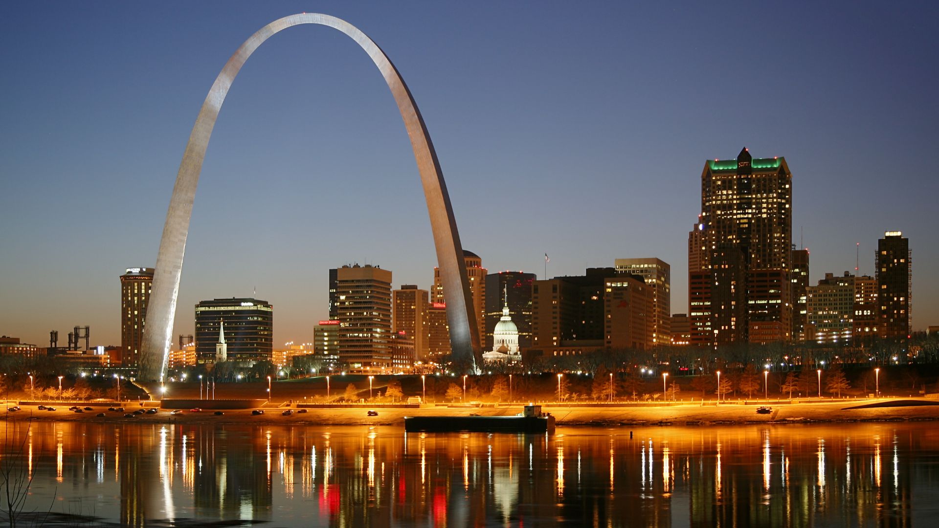 St. Louis on the Mississippi river by night. Jefferson National Expansion Memorial aka. Gateway Arch and Old Courthouse are visible.