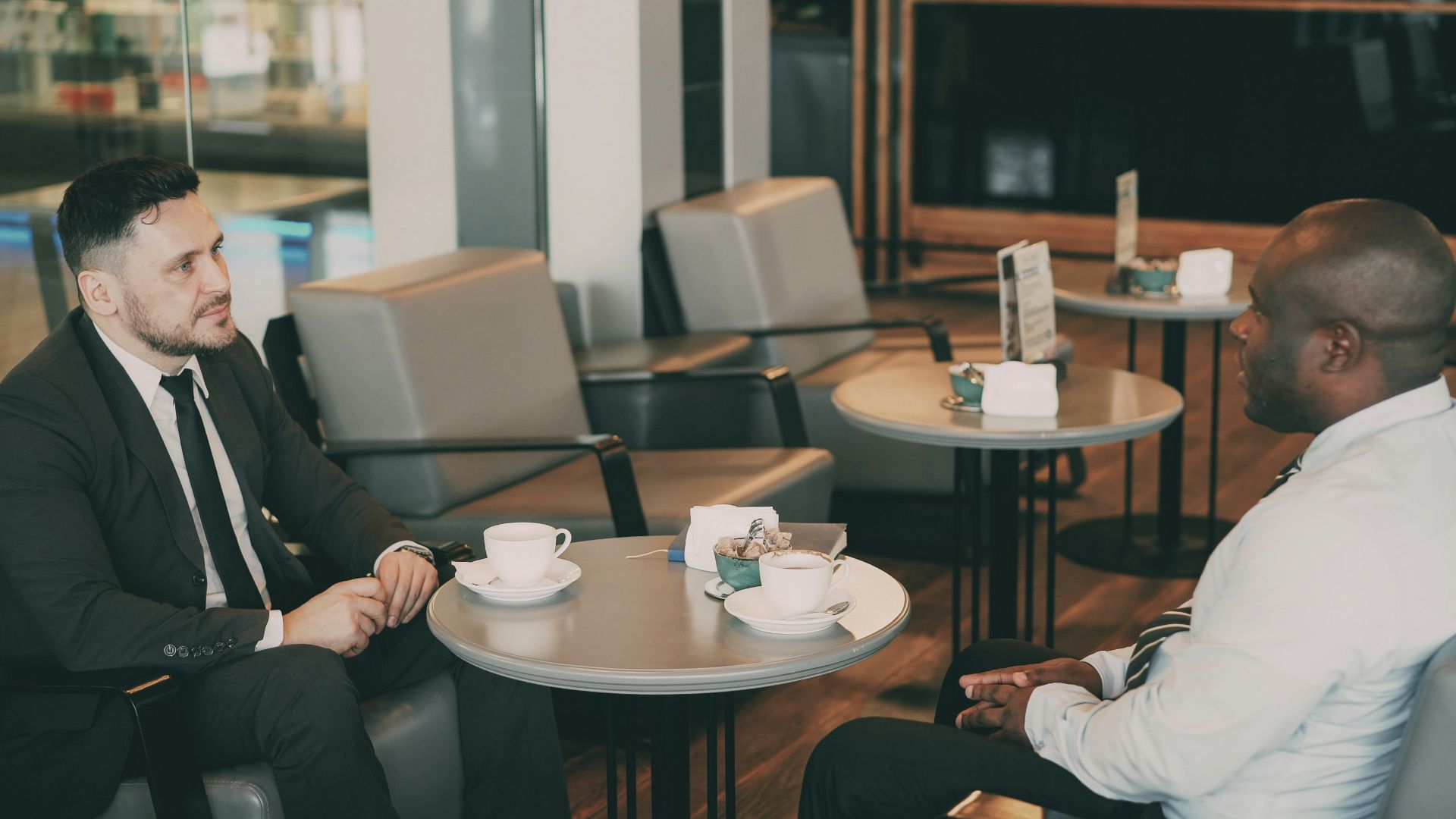 Two men in suits talking at a cafe
