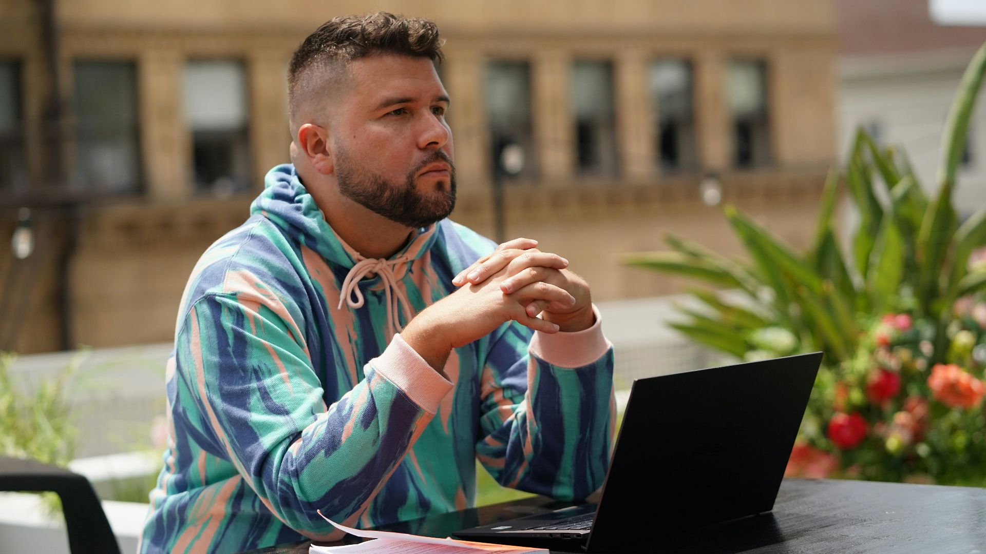 man in blue and white tribal print hoodie sitting beside black laptop computer