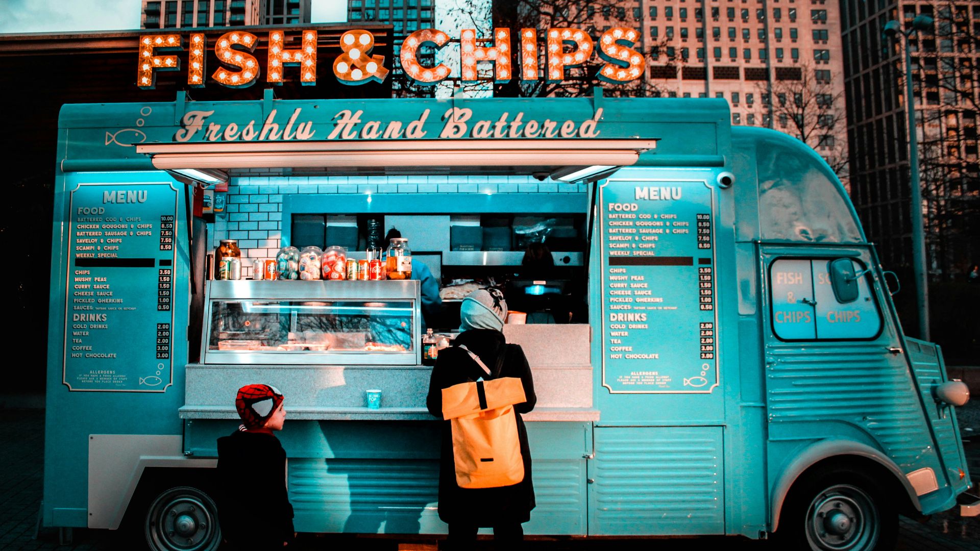 woman in brown coat standing in front of food stall