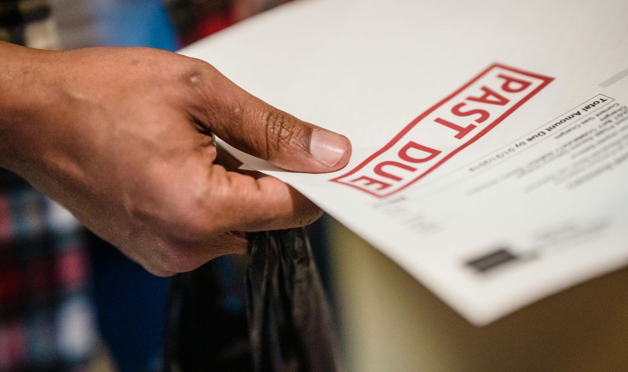 Hand of a Man Holding a Bill with Past Due Stamp