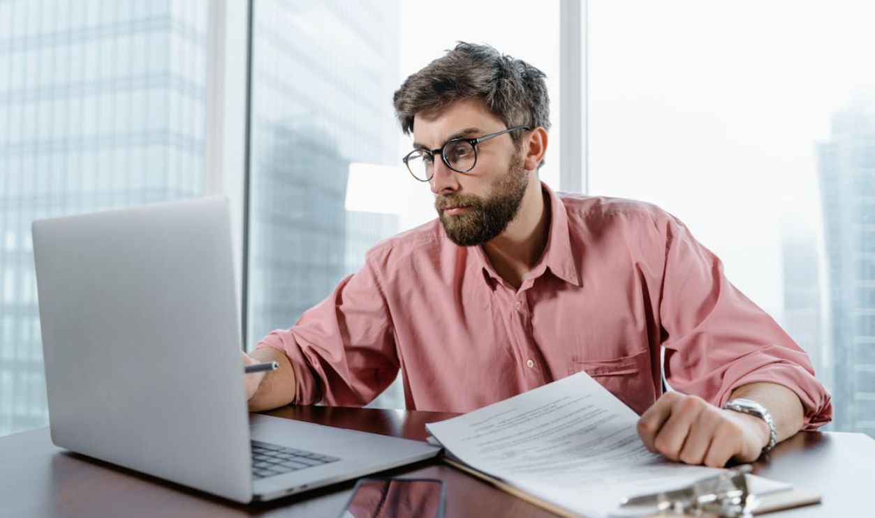 Man in Red Dress Shirt Wearing Black Framed Eyeglasses Using Macbook Air