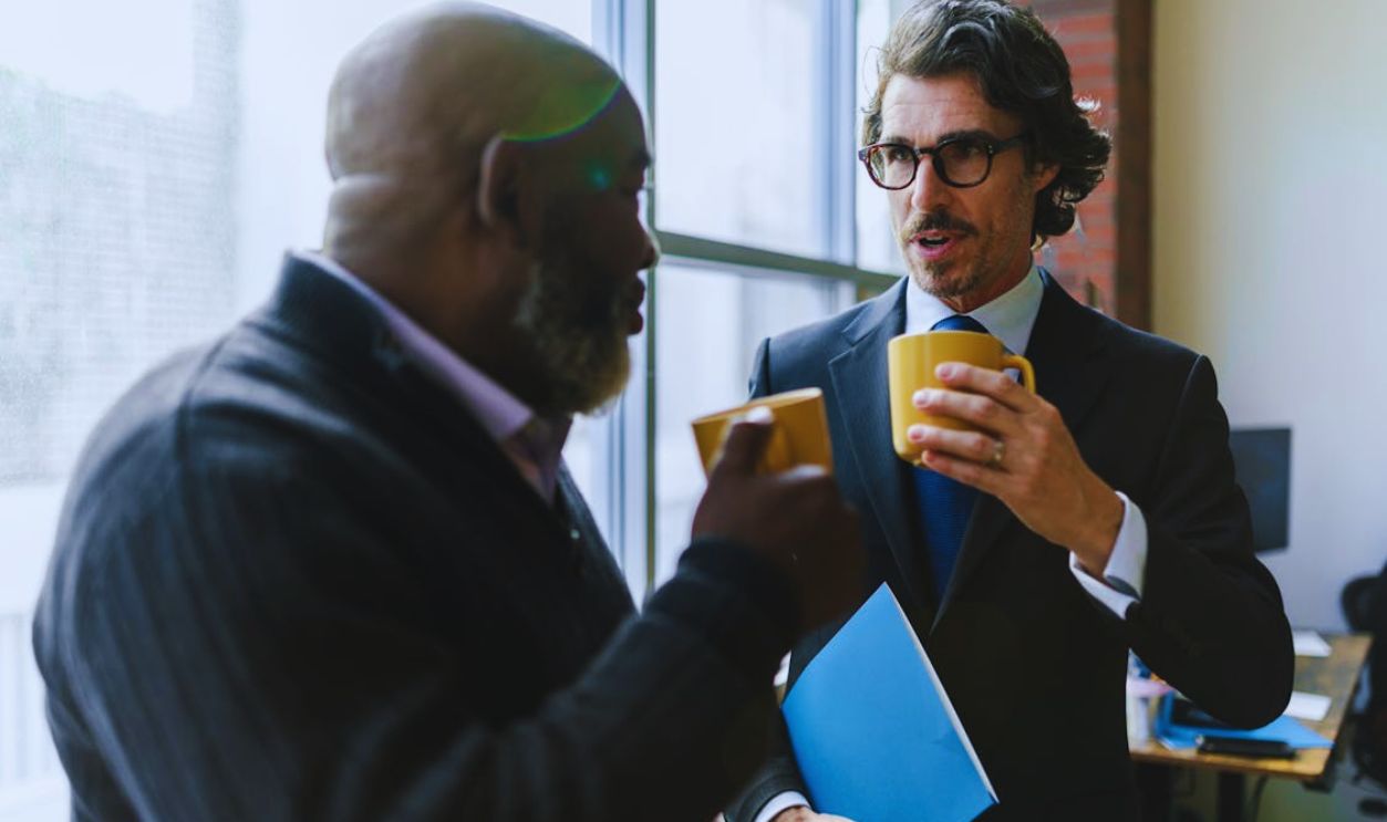 Men Having Conversation while Holding Mugs