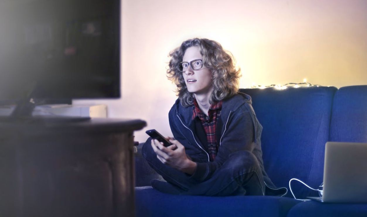 Young man using smartphone and watching TV in living room
