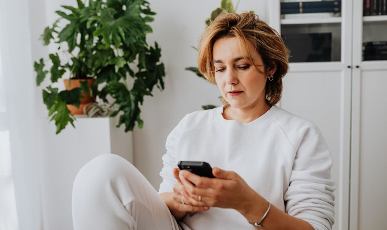 Close-Up Photo of a Woman in a White Long Sleeve Shirt Using Her Cell Phone
