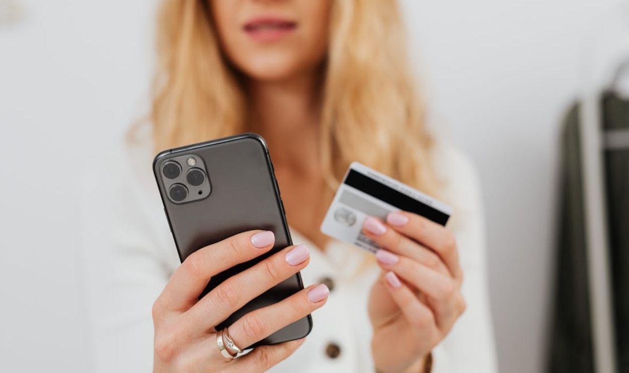 Close-Up Shot of a Woman Holding a Credit Card and Smartphone