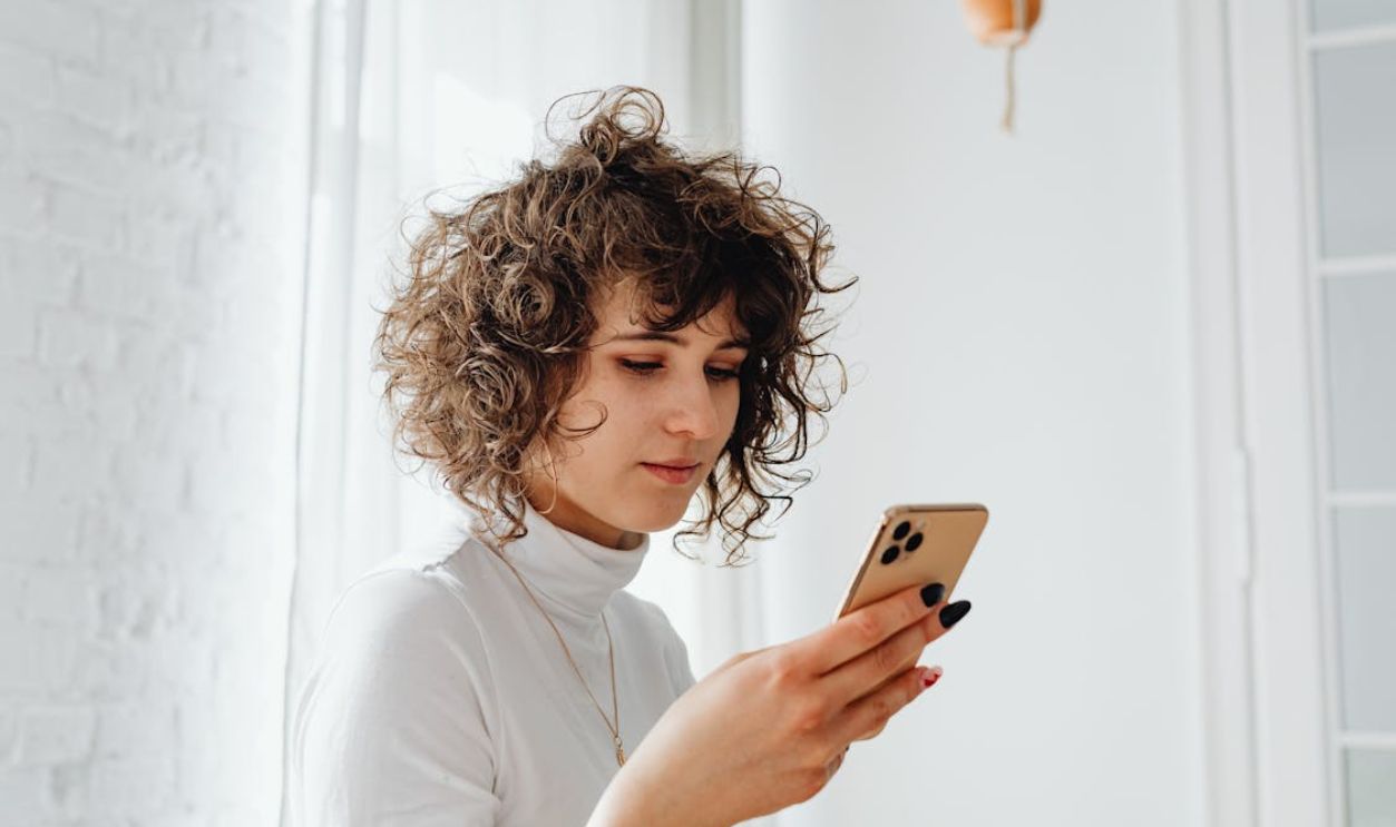 Woman in Turtleneck Shirt Using a Cellphone