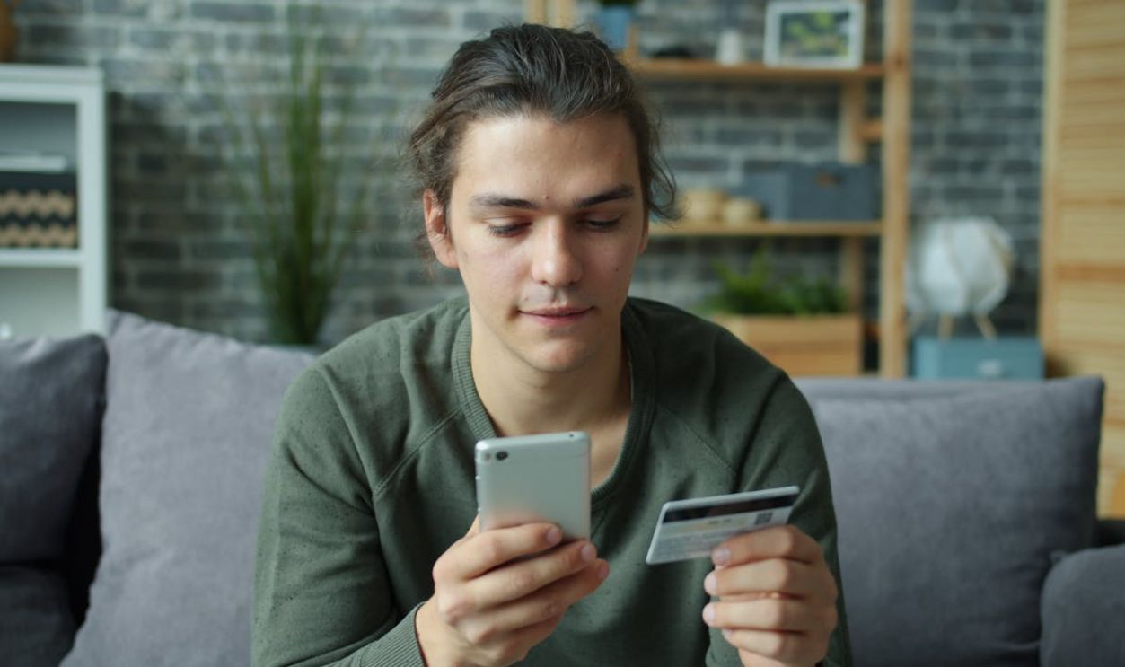Young Man Shopping Online with Smartphone and Card