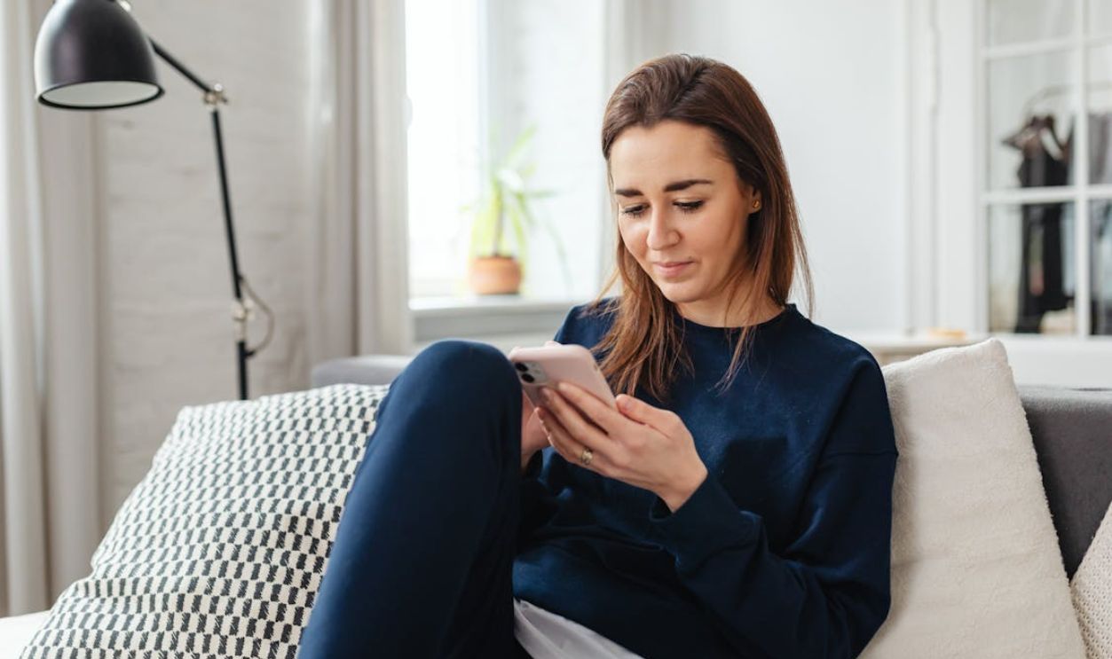 A Woman in Blue Long Sleeves Using Her Mobile Phone While Sitting