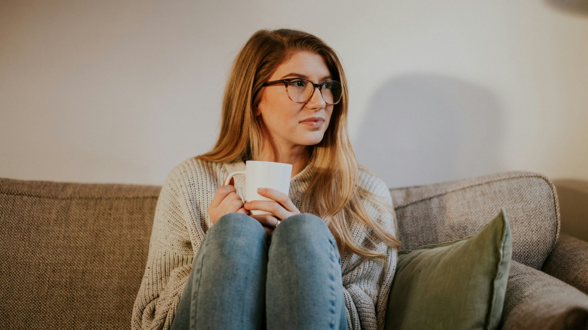 woman in blue denim jeans sitting on gray sofa