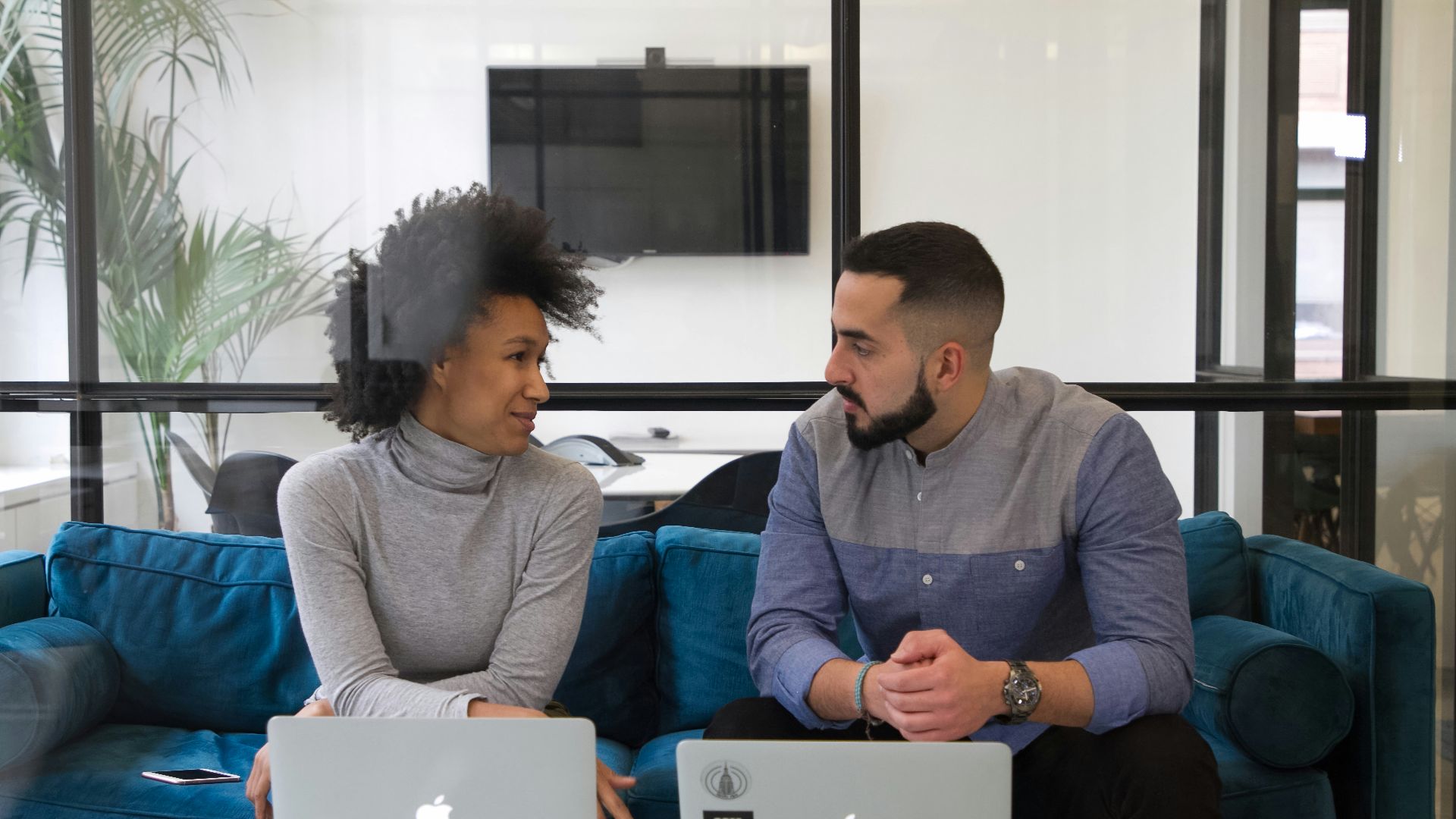 a man and a woman sitting on a couch with laptops