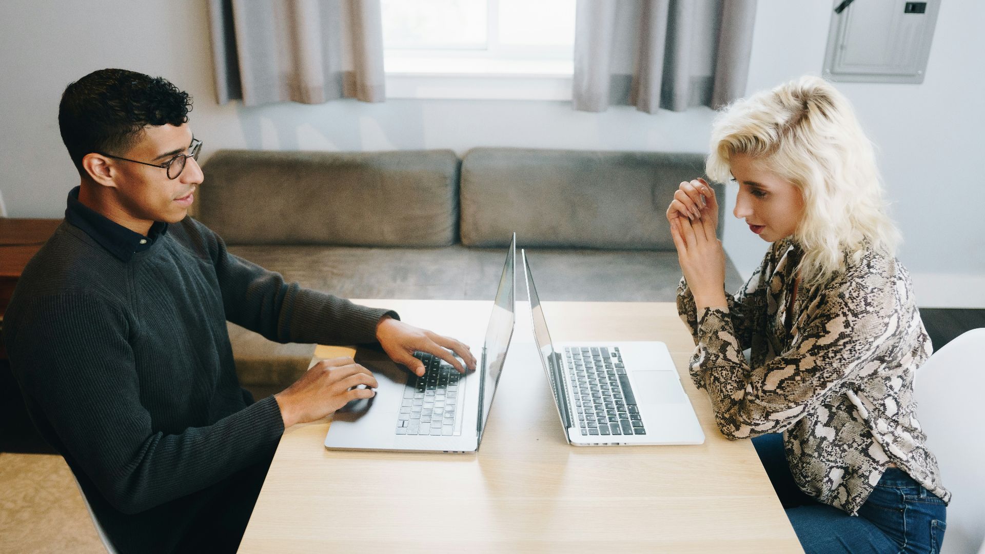 a man and woman sitting at a table with laptops