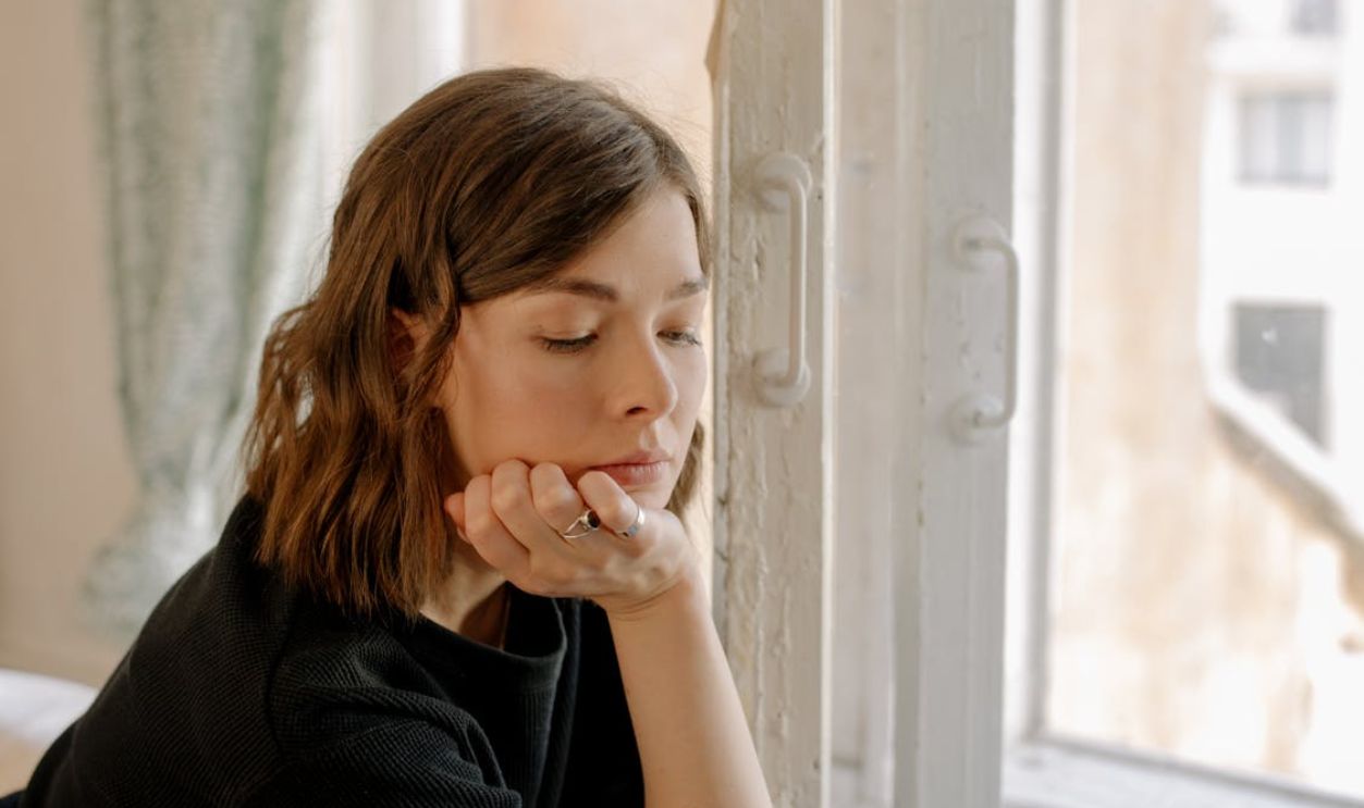 Woman in Black Shirt Leaning on White Wooden Window