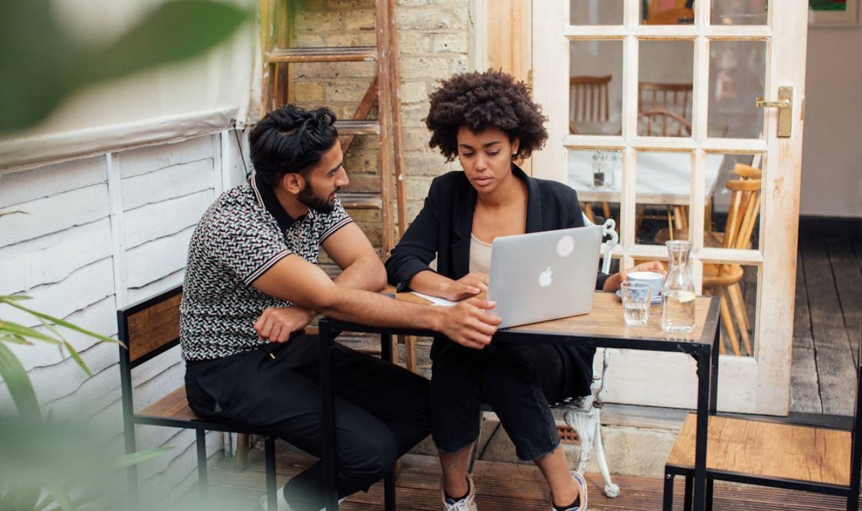 Couple Sitting by the Table with a Laptop