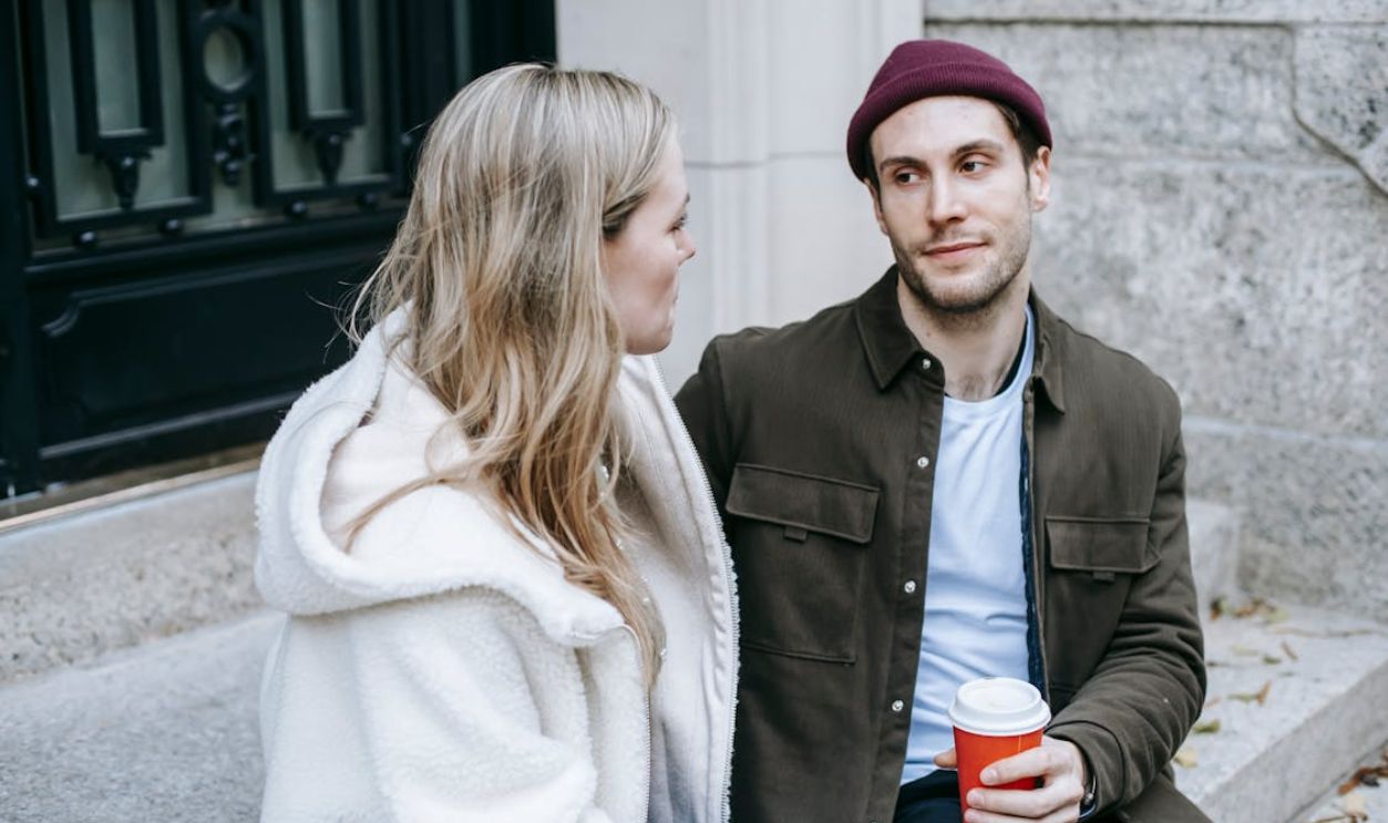 Young man and woman speaking sitting on steps beside house
