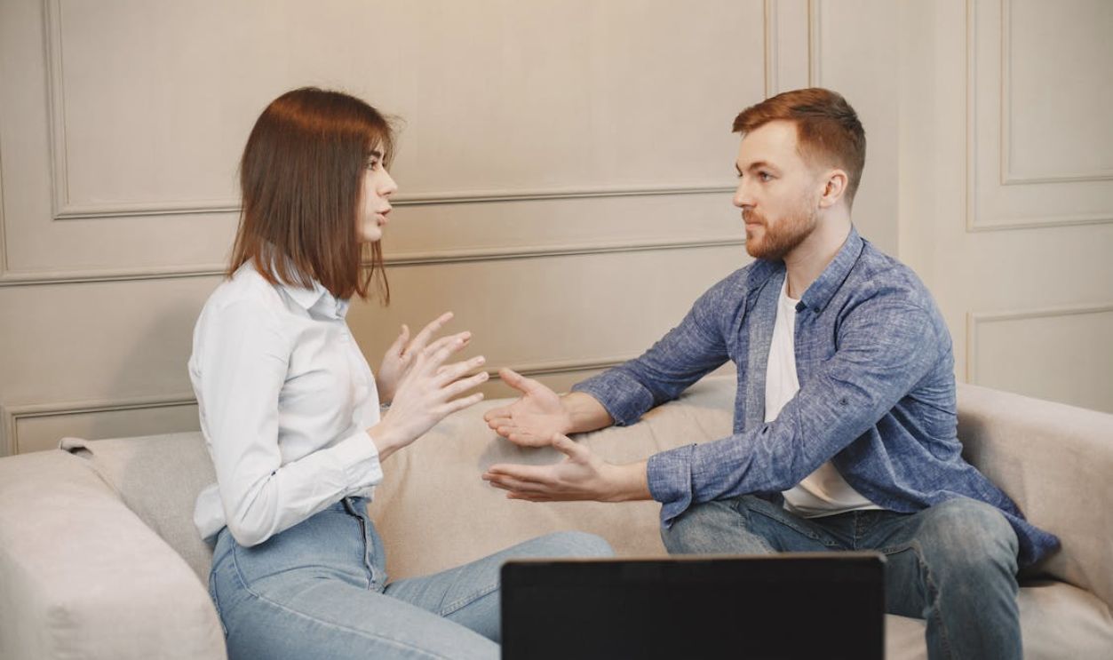 Close-Up Shot of a Man and a Woman Talking while Sitting on a Couch