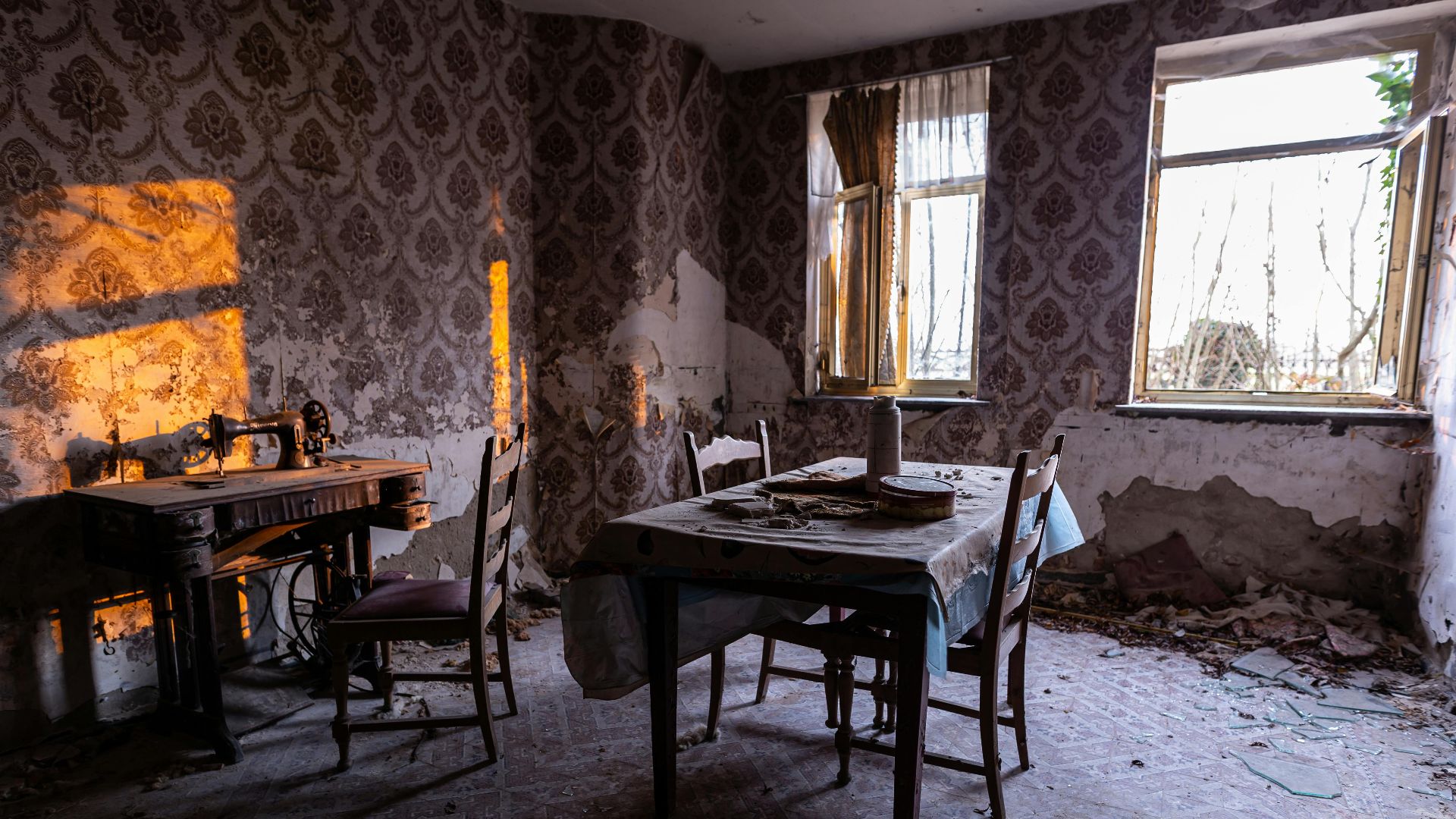 An atmospheric room in disrepair with vintage furniture and sunlight streaming through windows.