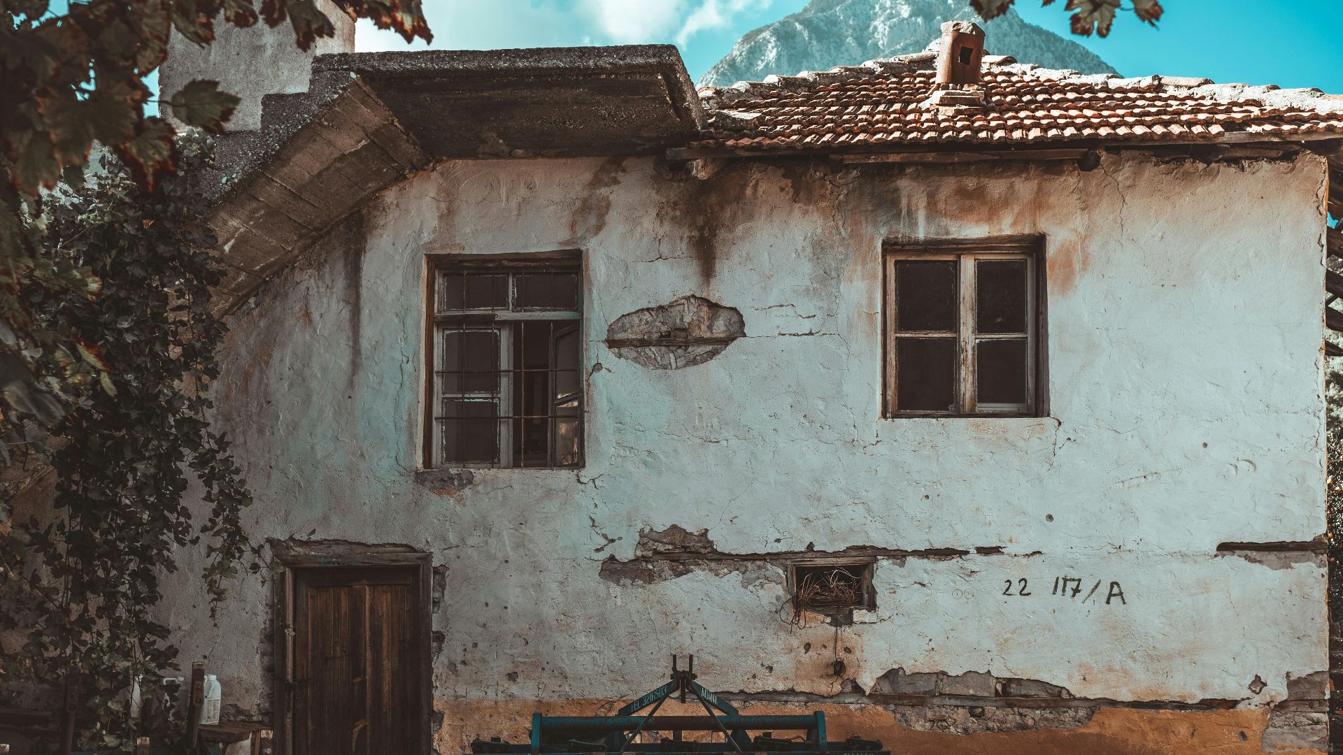 An old rural house featuring cracked walls and vintage windows, embodying rustic charm.