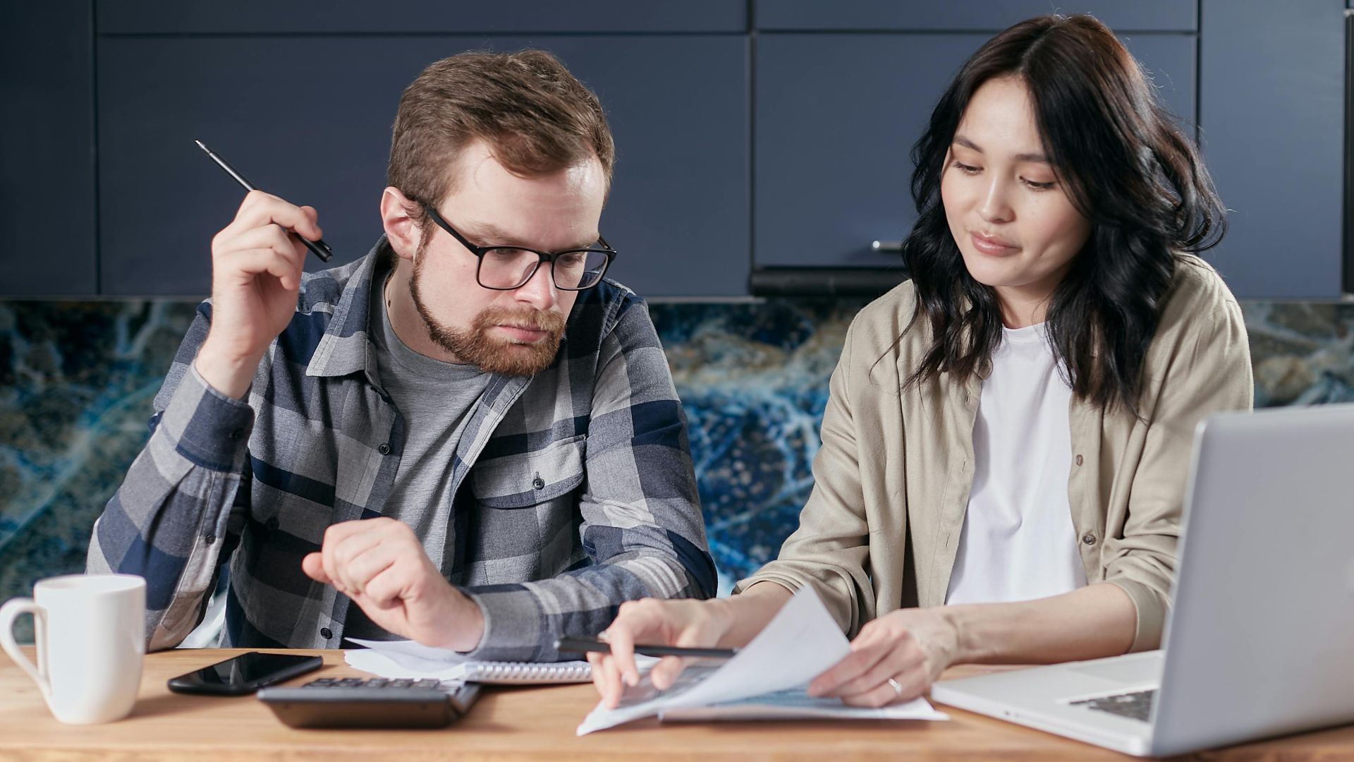 A couple is reviewing and calculating their household bills together at home.