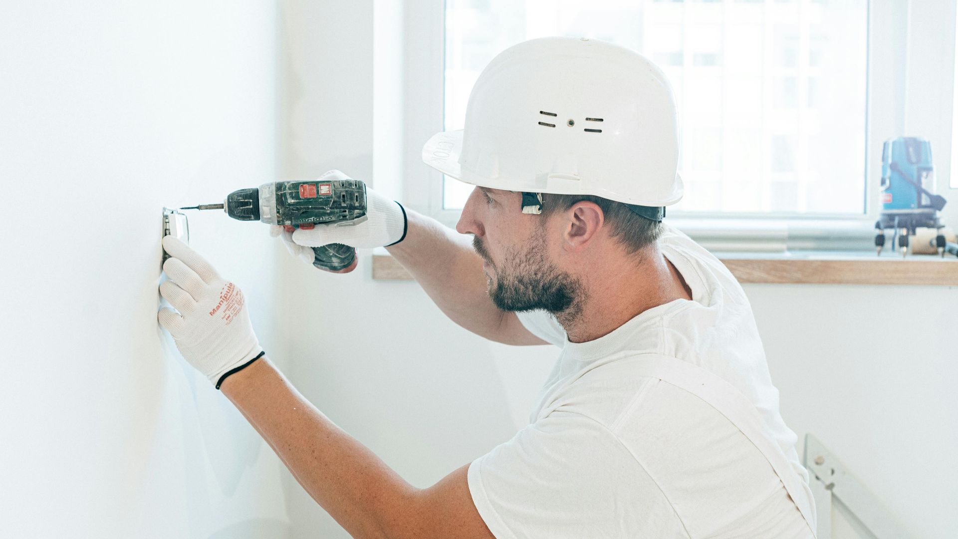 Carpenter skillfully uses a drill wearing safety gear during a renovation project indoors.