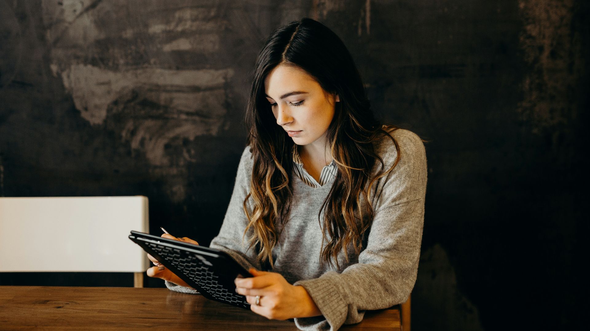 woman wearing white dress shirt using holding black leather case on brown wooden table