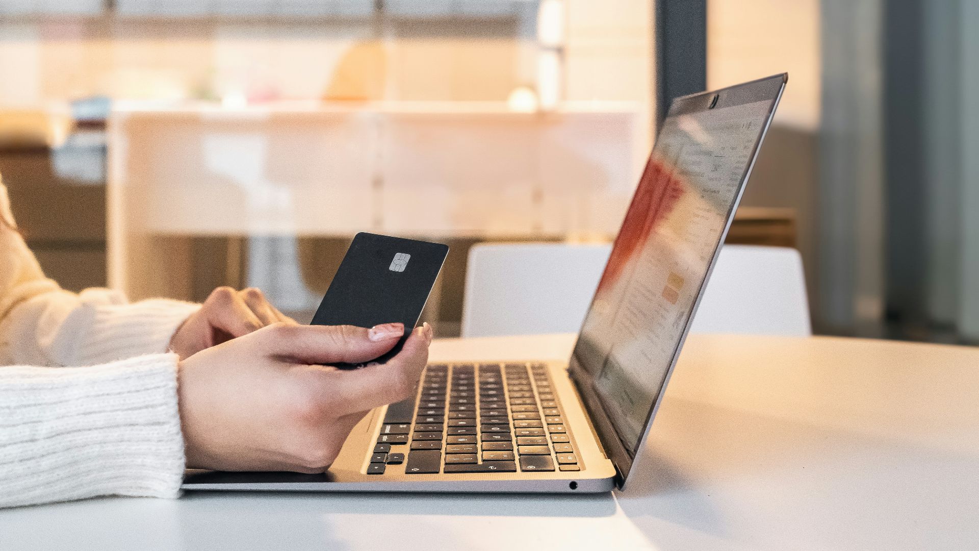 a woman sitting in front of a laptop computer holding a cell phone
