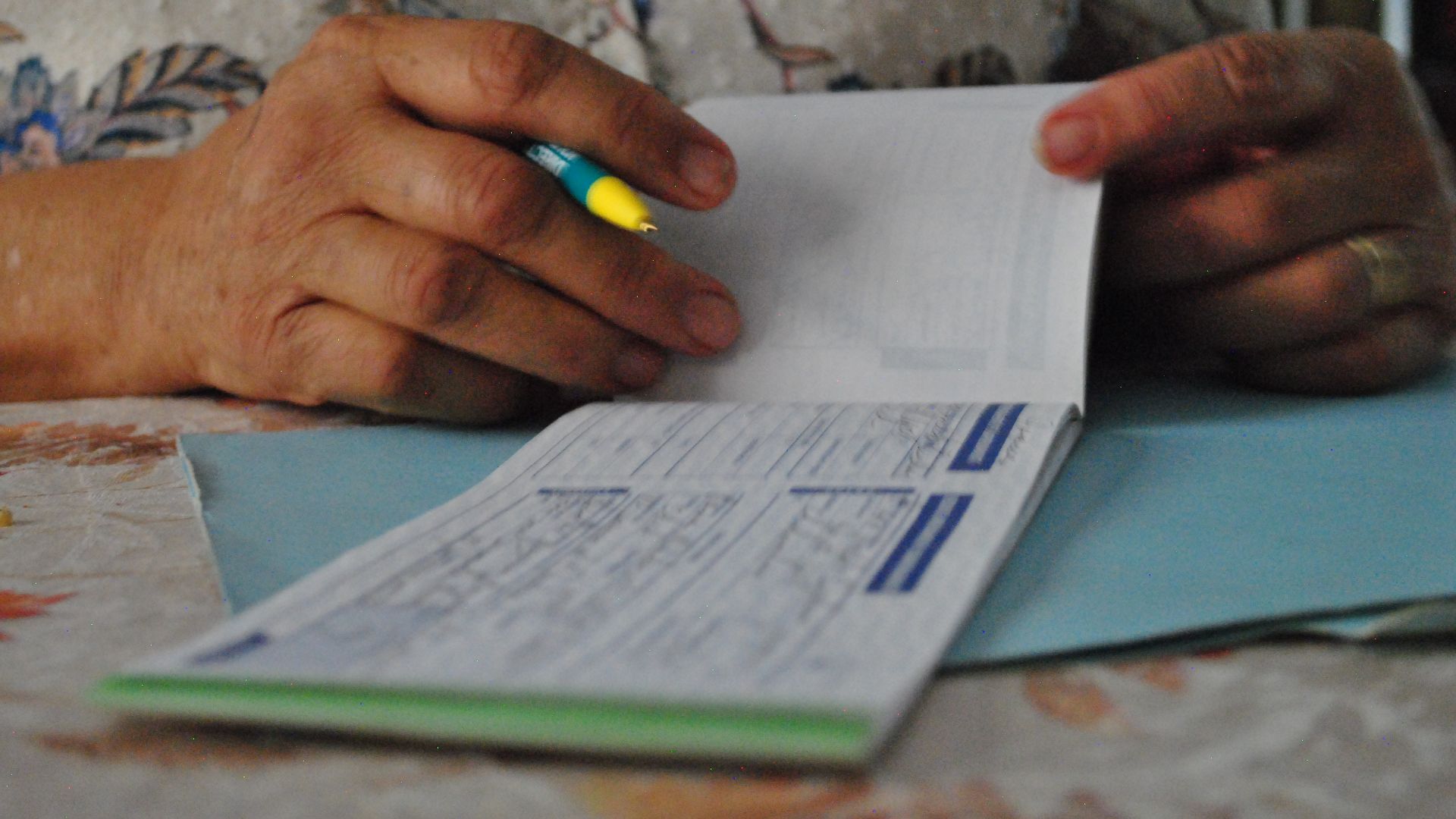 Senora mayor escribiendo un cheque ante uno de sus clientes