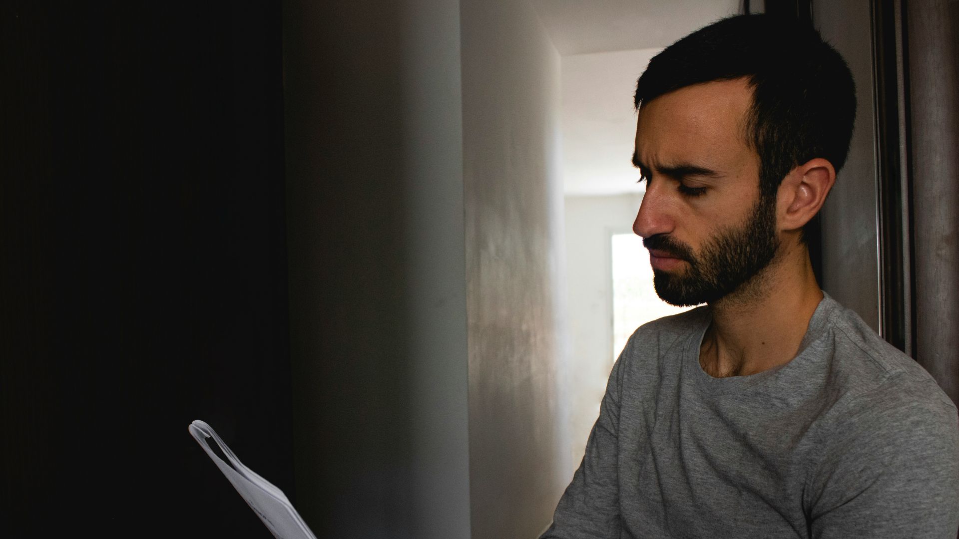 man in gray crew neck shirt holding white printer paper