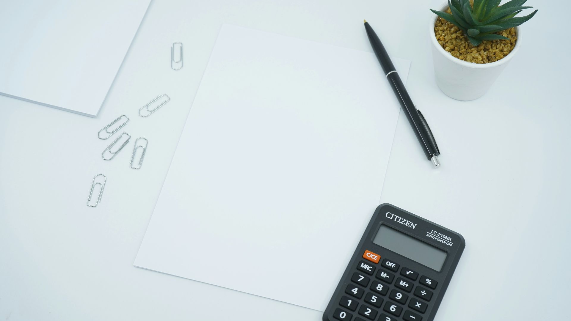 black calculator beside black pen on white printer paper