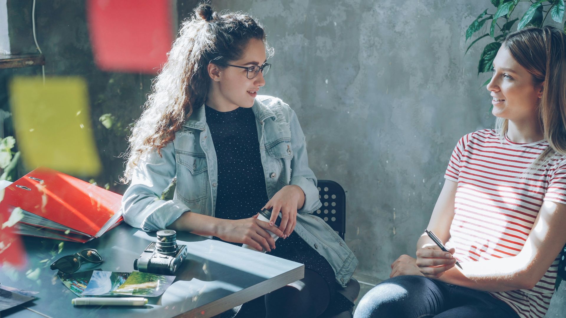 Two women are having a conversation at a table.