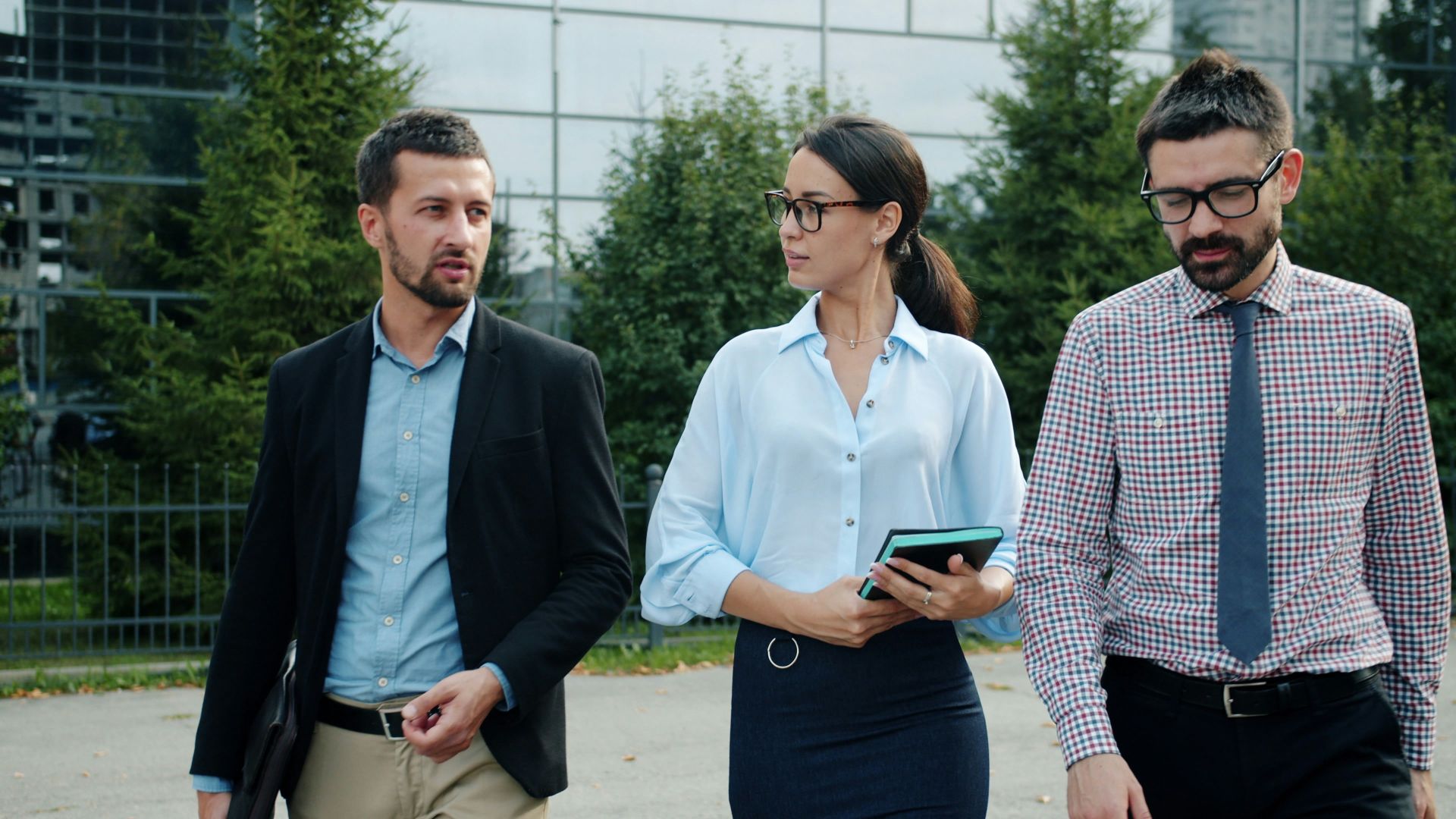Three business people walking outside an office building.