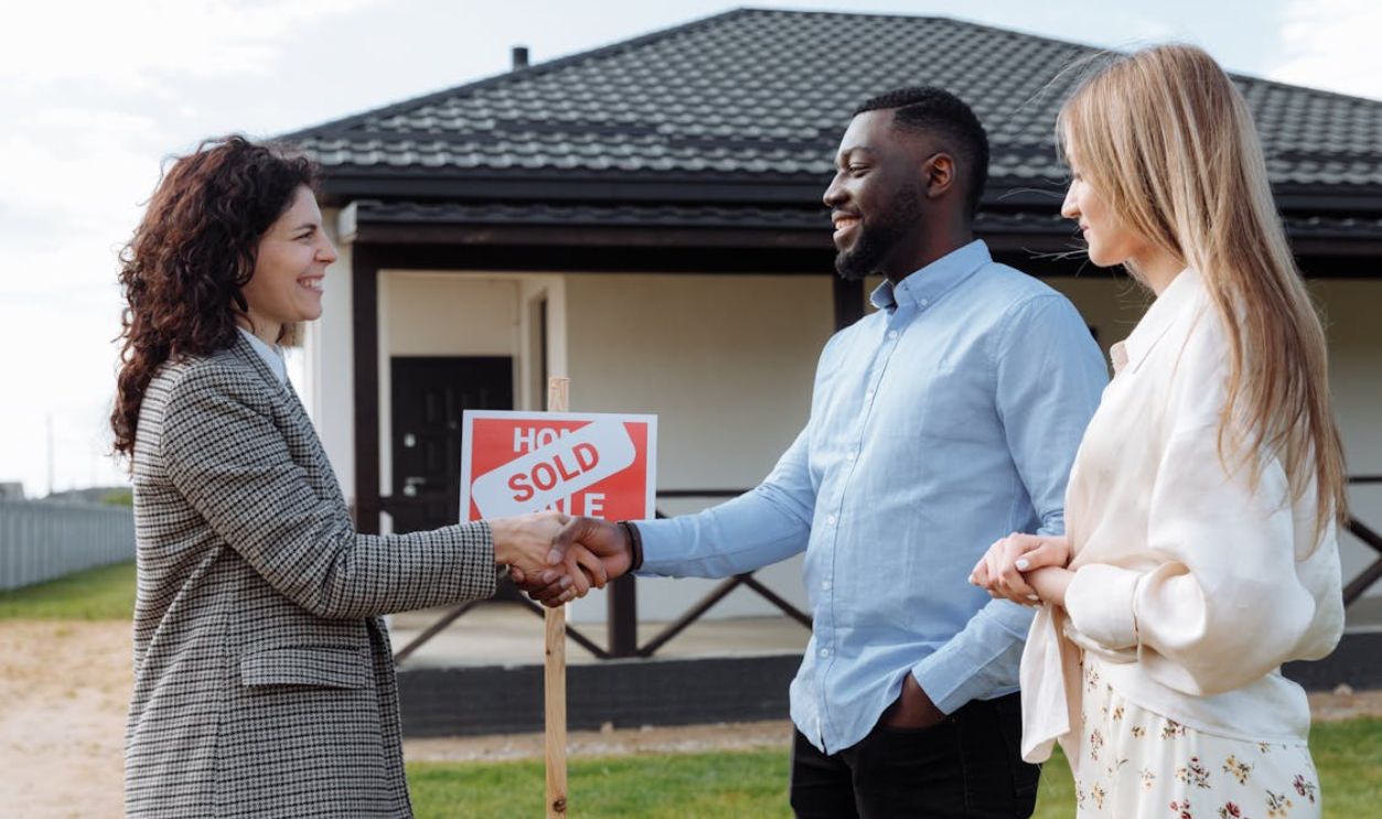 A Woman in Plaid Blazer Smiling while Doing Handshake with the Man in Blue Long Sleeves