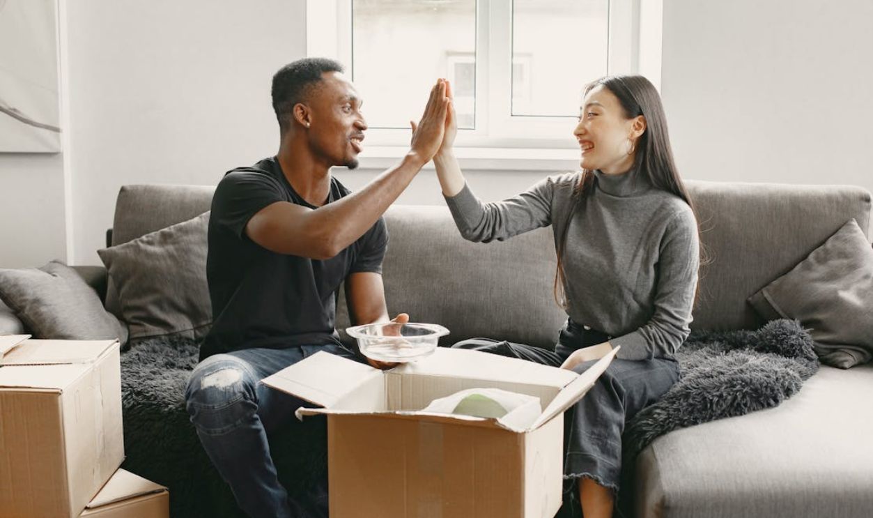 Man and Woman Sitting on Couch Unpacking Boxes