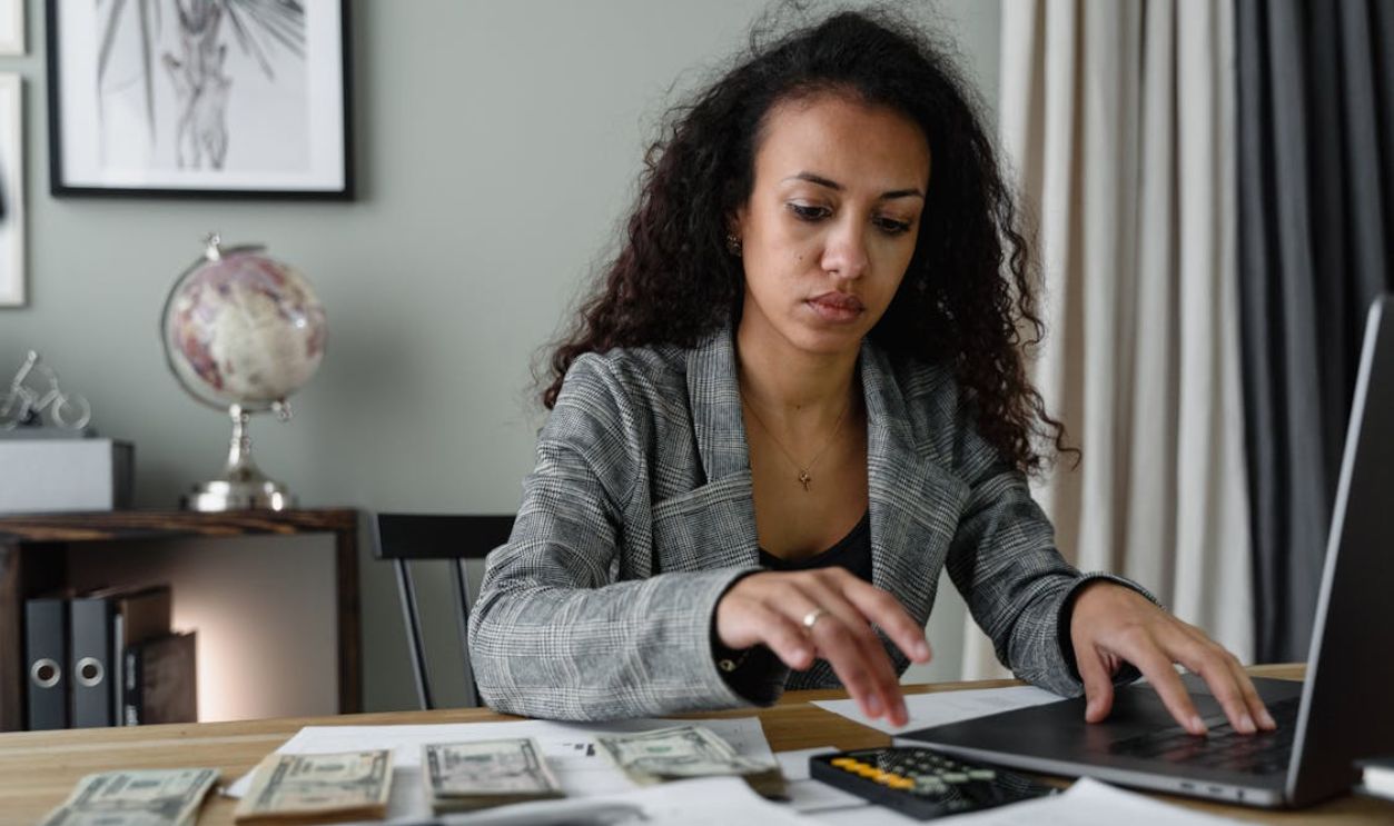 A Woman in Plaid Blazer Using Her Laptop and Mobile Phone