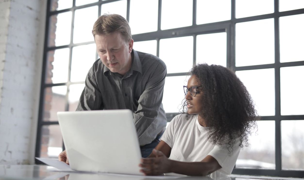 Concentrated diverse coworkers of different age with laptop and documents during office work