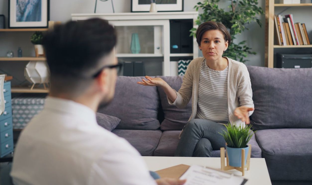 A woman and man sitting on a couch talking