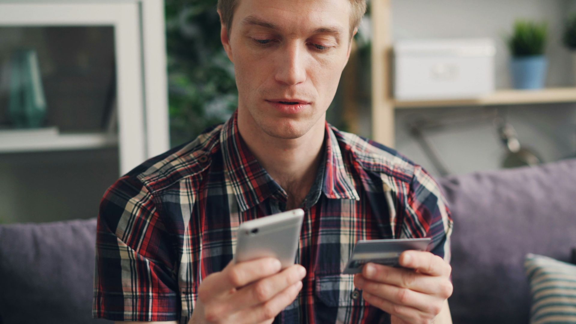 a man sitting on a couch looking at his cell phone