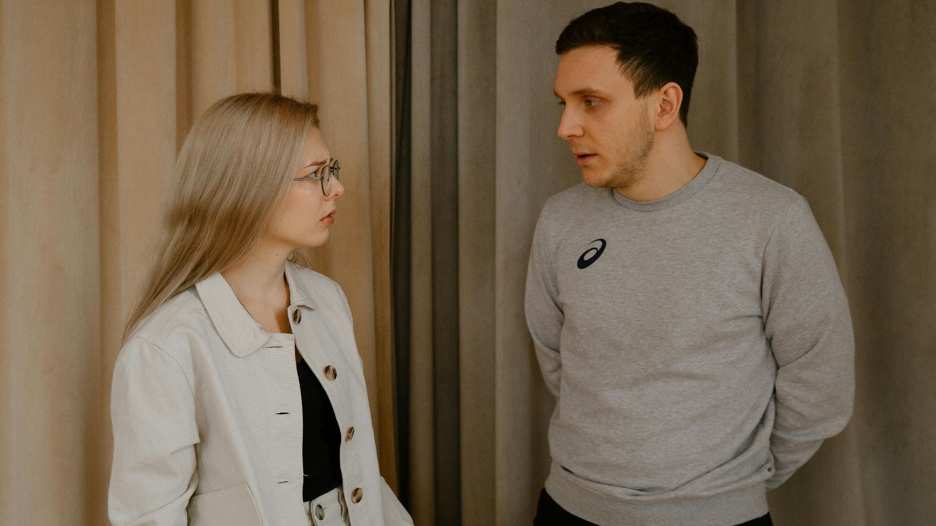 Man and woman having a serious conversation indoors, focused expressions.