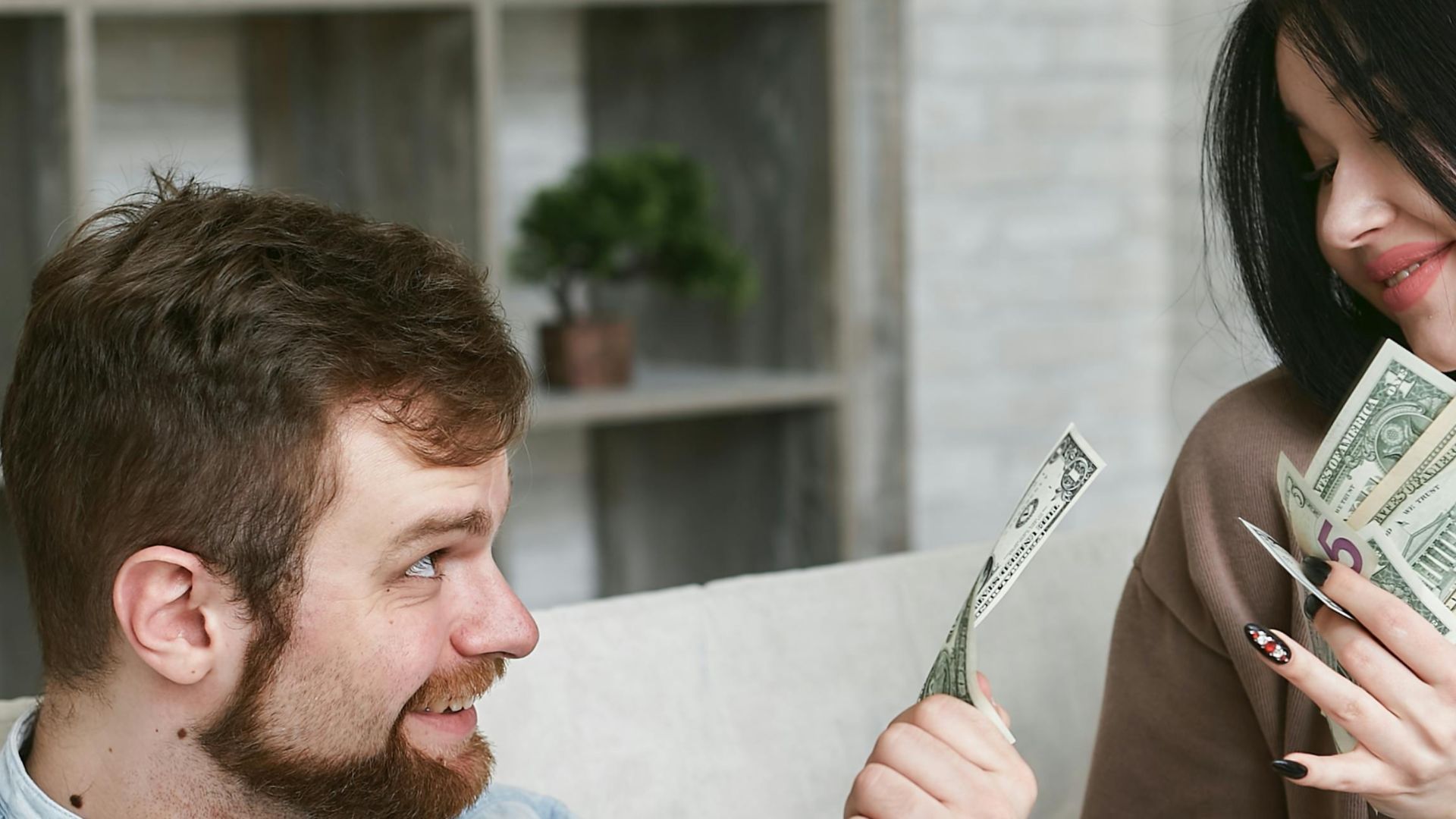 A cheerful couple managing their finances at home, holding cash and a receipt.