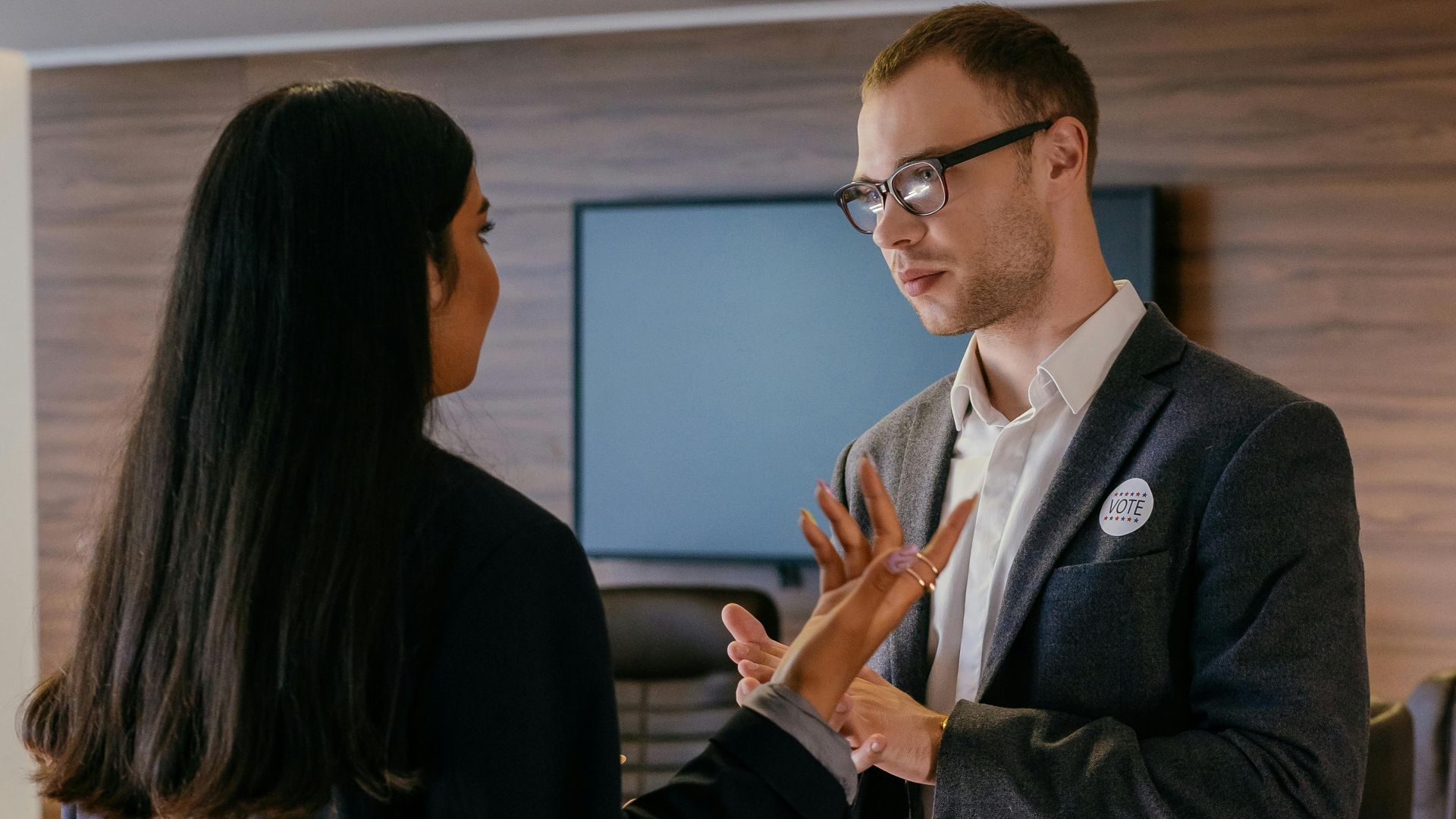 Two professionals engaged in conversation in a modern conference room setting.