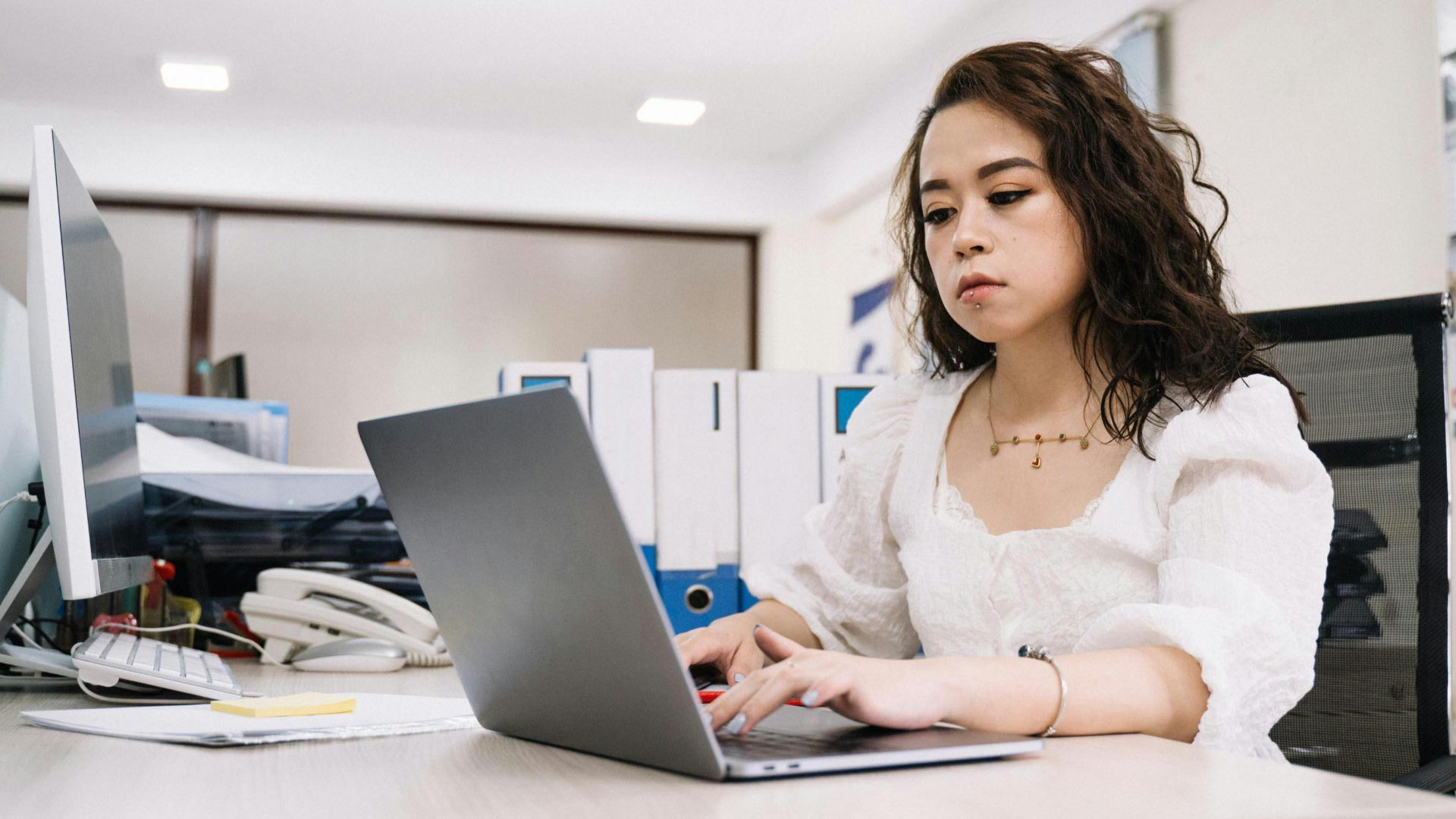 Professional woman working on a laptop in a modern office environment.