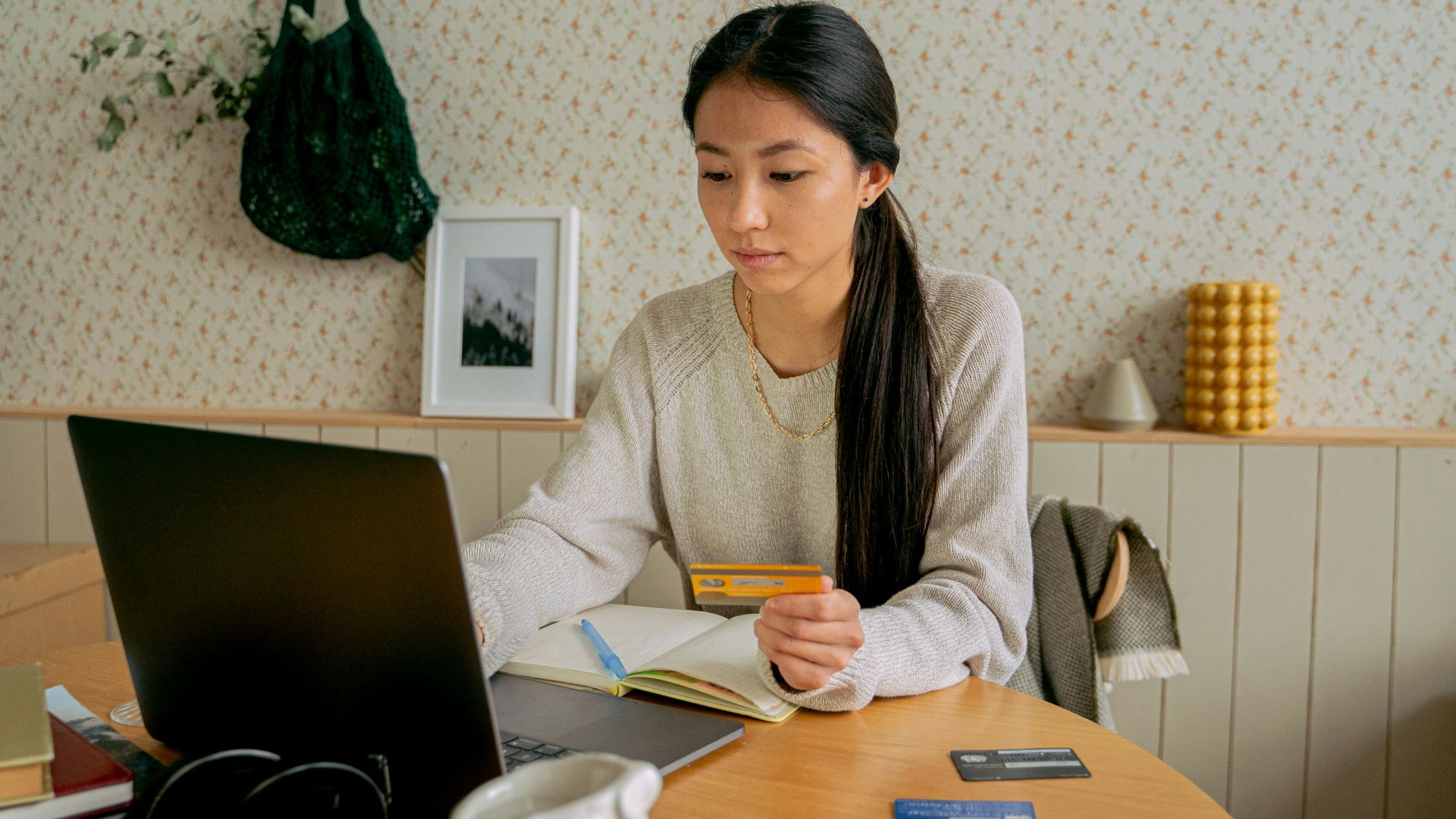 A woman using a laptop and credit card for online shopping at a cozy indoor setting.